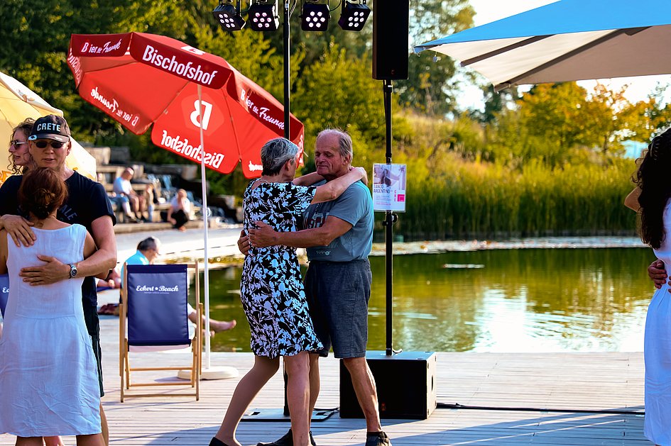 Die Bilder zeigen Impressionen der Tango Nacht am Eckert Beach mit Tanzpaaren, Schnupperkurs, Live-DJ, sommerlicher Atmosphäre und zahlreichen Gästen, die den Abschluss der Summer-Vibes-Reihe gemeinsam genießen.