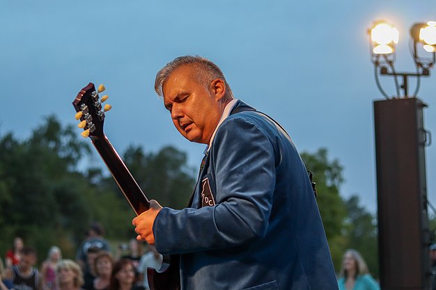Die Bilder zeigen Eindrücke der Rock-Nacht am Eckert Beach. Zu sehen sind die Live-Auftritte der Bands Rusty Road Runners und ACBarbingCity´25, zahlreiche Besucherinnen und Besucher vor der Bühne sowie die sommerliche Atmosphäre am Strand. In beiden Bands stehen auch Dozenten der Eckert Schulen auf der Bühne. Die Aufnahmen zeigen Musiker, Publikum und die stimmungsvolle Beleuchtung während des Open-Air-Konzerts.