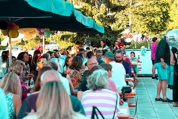 Gäste genießen gemeinsam die ausgelassene Atmosphäre bei der 80er-Jahre-Party am Eckert Beach.
