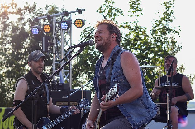 Die Bilder zeigen Eindrücke der Rock-Nacht am Eckert Beach. Zu sehen sind die Live-Auftritte der Bands Rusty Road Runners und ACBarbingCity´25, zahlreiche Besucherinnen und Besucher vor der Bühne sowie die sommerliche Atmosphäre am Strand. In beiden Bands stehen auch Dozenten der Eckert Schulen auf der Bühne. Die Aufnahmen zeigen Musiker, Publikum und die stimmungsvolle Beleuchtung während des Open-Air-Konzerts.
