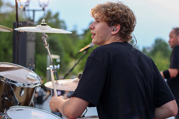 Die Bilder zeigen Eindrücke der Rock-Nacht am Eckert Beach. Zu sehen sind die Live-Auftritte der Bands Rusty Road Runners und ACBarbingCity´25, zahlreiche Besucherinnen und Besucher vor der Bühne sowie die sommerliche Atmosphäre am Strand. In beiden Bands stehen auch Dozenten der Eckert Schulen auf der Bühne. Die Aufnahmen zeigen Musiker, Publikum und die stimmungsvolle Beleuchtung während des Open-Air-Konzerts.