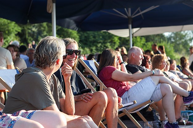 Die Bilder zeigen Eindrücke der Rock-Nacht am Eckert Beach. Zu sehen sind die Live-Auftritte der Bands Rusty Road Runners und ACBarbingCity´25, zahlreiche Besucherinnen und Besucher vor der Bühne sowie die sommerliche Atmosphäre am Strand. In beiden Bands stehen auch Dozenten der Eckert Schulen auf der Bühne. Die Aufnahmen zeigen Musiker, Publikum und die stimmungsvolle Beleuchtung während des Open-Air-Konzerts.