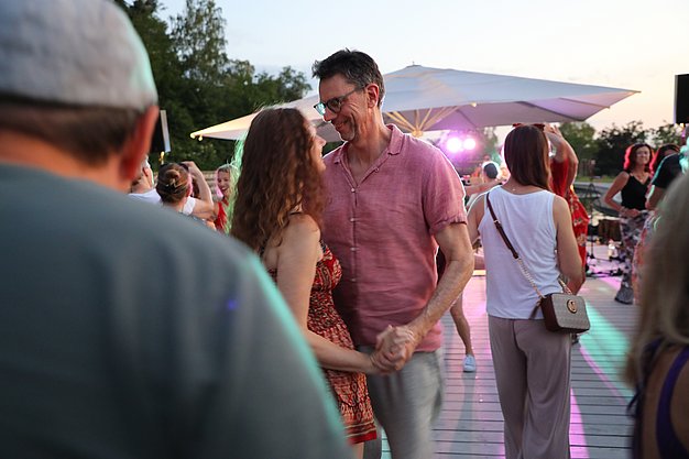 Die Diashow zeigt Eindrücke vom Salsa-Abend am Eckert Beach. Zu sehen sind tanzende Paare, Besucherinnen und Besucher im Publikum sowie die stimmungsvolle Atmosphäre der Veranstaltung am Abend.