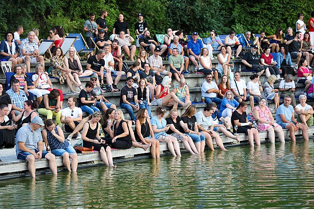 Die Bilder zeigen Eindrücke der Rock-Nacht am Eckert Beach. Zu sehen sind die Live-Auftritte der Bands Rusty Road Runners und ACBarbingCity´25, zahlreiche Besucherinnen und Besucher vor der Bühne sowie die sommerliche Atmosphäre am Strand. In beiden Bands stehen auch Dozenten der Eckert Schulen auf der Bühne. Die Aufnahmen zeigen Musiker, Publikum und die stimmungsvolle Beleuchtung während des Open-Air-Konzerts.