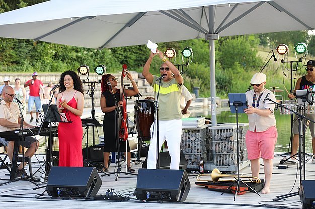 Die Diashow zeigt Eindrücke vom Salsa-Abend am Eckert Beach. Zu sehen sind tanzende Paare, Besucherinnen und Besucher im Publikum sowie die stimmungsvolle Atmosphäre der Veranstaltung am Abend.