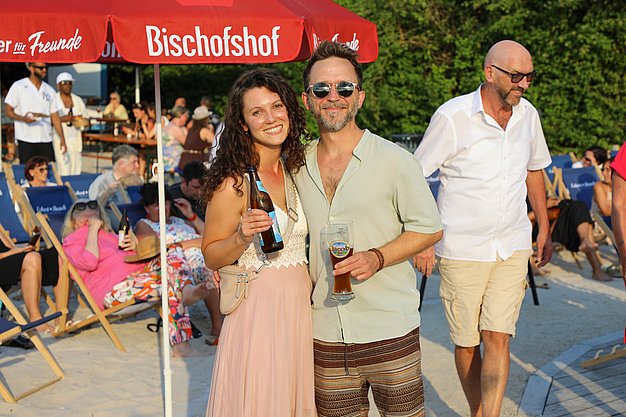 Die Diashow zeigt Eindrücke vom Salsa-Abend am Eckert Beach. Zu sehen sind tanzende Paare, Besucherinnen und Besucher im Publikum sowie die stimmungsvolle Atmosphäre der Veranstaltung am Abend.