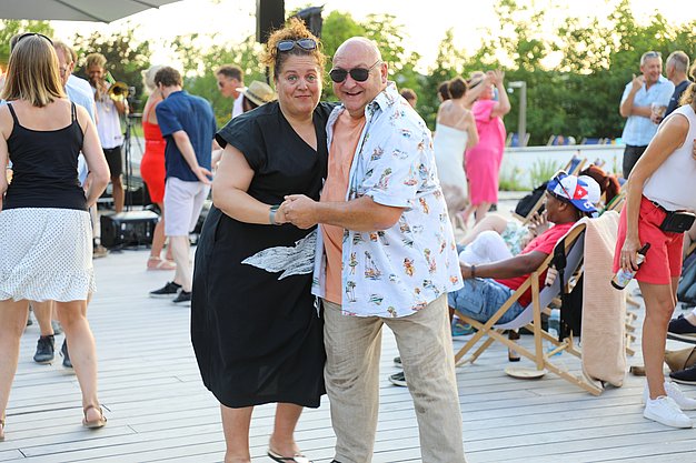 Die Diashow zeigt Eindrücke vom Salsa-Abend am Eckert Beach. Zu sehen sind tanzende Paare, Besucherinnen und Besucher im Publikum sowie die stimmungsvolle Atmosphäre der Veranstaltung am Abend.