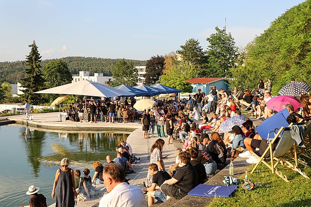 Die Bilder zeigen Eindrücke der Rock-Nacht am Eckert Beach. Zu sehen sind die Live-Auftritte der Bands Rusty Road Runners und ACBarbingCity´25, zahlreiche Besucherinnen und Besucher vor der Bühne sowie die sommerliche Atmosphäre am Strand. In beiden Bands stehen auch Dozenten der Eckert Schulen auf der Bühne. Die Aufnahmen zeigen Musiker, Publikum und die stimmungsvolle Beleuchtung während des Open-Air-Konzerts.