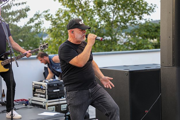 Die Bilder zeigen Eindrücke der Rock-Nacht am Eckert Beach. Zu sehen sind die Live-Auftritte der Bands Rusty Road Runners und ACBarbingCity´25, zahlreiche Besucherinnen und Besucher vor der Bühne sowie die sommerliche Atmosphäre am Strand. In beiden Bands stehen auch Dozenten der Eckert Schulen auf der Bühne. Die Aufnahmen zeigen Musiker, Publikum und die stimmungsvolle Beleuchtung während des Open-Air-Konzerts.