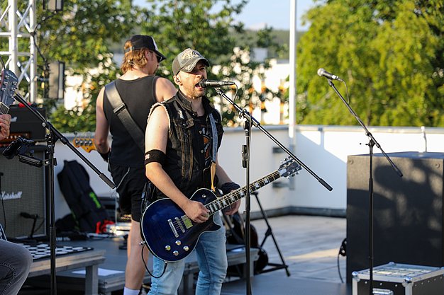 Die Bilder zeigen Eindrücke der Rock-Nacht am Eckert Beach. Zu sehen sind die Live-Auftritte der Bands Rusty Road Runners und ACBarbingCity´25, zahlreiche Besucherinnen und Besucher vor der Bühne sowie die sommerliche Atmosphäre am Strand. In beiden Bands stehen auch Dozenten der Eckert Schulen auf der Bühne. Die Aufnahmen zeigen Musiker, Publikum und die stimmungsvolle Beleuchtung während des Open-Air-Konzerts.