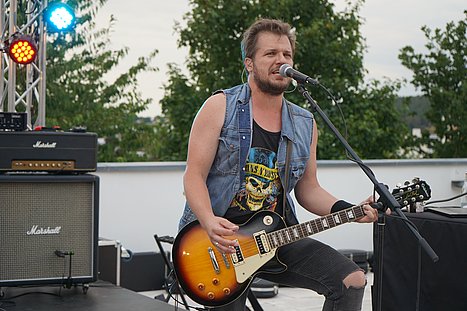 Mit Gitarre und starker Stimme: Die „Rock Road Runners“ bringen beim Open-Air auf dem Campus das Amphitheater zum Beben.