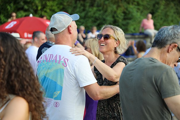 Die Diashow zeigt Eindrücke vom Salsa-Abend am Eckert Beach. Zu sehen sind tanzende Paare, Besucherinnen und Besucher im Publikum sowie die stimmungsvolle Atmosphäre der Veranstaltung am Abend.