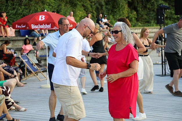 Die Diashow zeigt Eindrücke vom Salsa-Abend am Eckert Beach. Zu sehen sind tanzende Paare, Besucherinnen und Besucher im Publikum sowie die stimmungsvolle Atmosphäre der Veranstaltung am Abend.