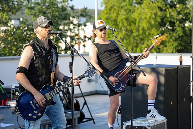 Die Bilder zeigen Eindrücke der Rock-Nacht am Eckert Beach. Zu sehen sind die Live-Auftritte der Bands Rusty Road Runners und ACBarbingCity´25, zahlreiche Besucherinnen und Besucher vor der Bühne sowie die sommerliche Atmosphäre am Strand. In beiden Bands stehen auch Dozenten der Eckert Schulen auf der Bühne. Die Aufnahmen zeigen Musiker, Publikum und die stimmungsvolle Beleuchtung während des Open-Air-Konzerts.