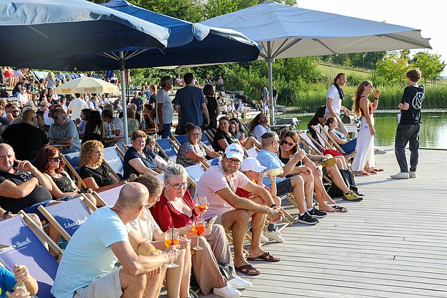 Die Bilder zeigen Eindrücke der Rock-Nacht am Eckert Beach. Zu sehen sind die Live-Auftritte der Bands Rusty Road Runners und ACBarbingCity´25, zahlreiche Besucherinnen und Besucher vor der Bühne sowie die sommerliche Atmosphäre am Strand. In beiden Bands stehen auch Dozenten der Eckert Schulen auf der Bühne. Die Aufnahmen zeigen Musiker, Publikum und die stimmungsvolle Beleuchtung während des Open-Air-Konzerts.