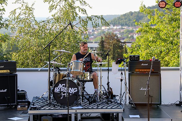 Die Bilder zeigen Eindrücke der Rock-Nacht am Eckert Beach. Zu sehen sind die Live-Auftritte der Bands Rusty Road Runners und ACBarbingCity´25, zahlreiche Besucherinnen und Besucher vor der Bühne sowie die sommerliche Atmosphäre am Strand. In beiden Bands stehen auch Dozenten der Eckert Schulen auf der Bühne. Die Aufnahmen zeigen Musiker, Publikum und die stimmungsvolle Beleuchtung während des Open-Air-Konzerts.