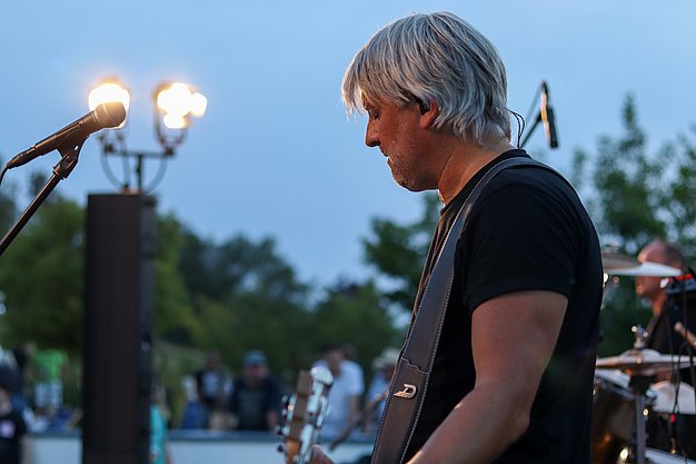 Die Bilder zeigen Eindrücke der Rock-Nacht am Eckert Beach. Zu sehen sind die Live-Auftritte der Bands Rusty Road Runners und ACBarbingCity´25, zahlreiche Besucherinnen und Besucher vor der Bühne sowie die sommerliche Atmosphäre am Strand. In beiden Bands stehen auch Dozenten der Eckert Schulen auf der Bühne. Die Aufnahmen zeigen Musiker, Publikum und die stimmungsvolle Beleuchtung während des Open-Air-Konzerts.