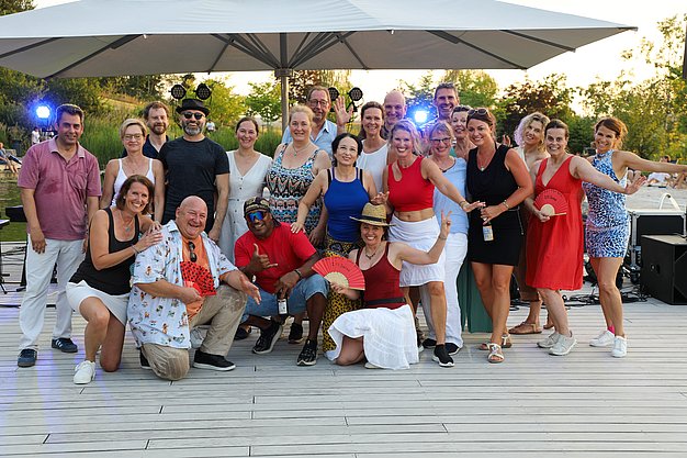 Die Diashow zeigt Eindrücke vom Salsa-Abend am Eckert Beach. Zu sehen sind tanzende Paare, Besucherinnen und Besucher im Publikum sowie die stimmungsvolle Atmosphäre der Veranstaltung am Abend.