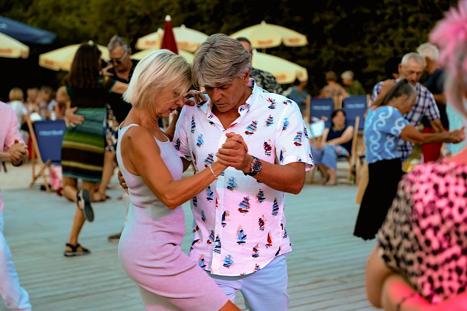 Die Bilder zeigen Impressionen der Tango Nacht am Eckert Beach mit Tanzpaaren, Schnupperkurs, Live-DJ, sommerlicher Atmosphäre und zahlreichen Gästen, die den Abschluss der Summer-Vibes-Reihe gemeinsam genießen.