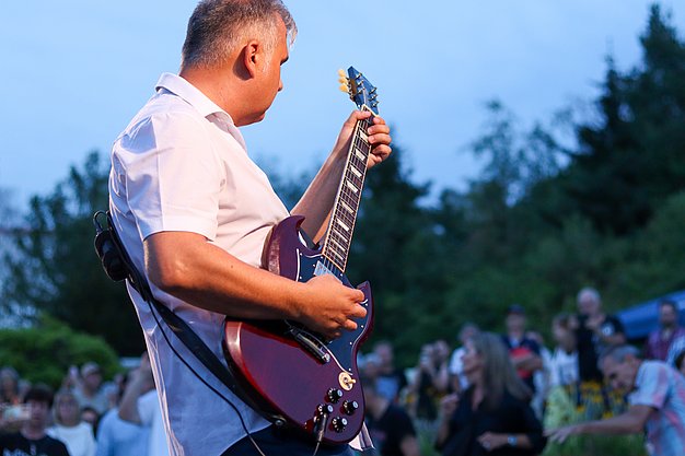 Die Bilder zeigen Eindrücke der Rock-Nacht am Eckert Beach. Zu sehen sind die Live-Auftritte der Bands Rusty Road Runners und ACBarbingCity´25, zahlreiche Besucherinnen und Besucher vor der Bühne sowie die sommerliche Atmosphäre am Strand. In beiden Bands stehen auch Dozenten der Eckert Schulen auf der Bühne. Die Aufnahmen zeigen Musiker, Publikum und die stimmungsvolle Beleuchtung während des Open-Air-Konzerts.