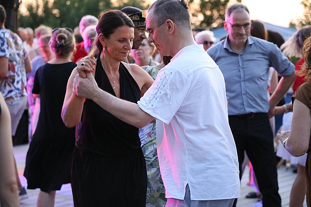 Die Diashow zeigt Eindrücke vom Salsa-Abend am Eckert Beach. Zu sehen sind tanzende Paare, Besucherinnen und Besucher im Publikum sowie die stimmungsvolle Atmosphäre der Veranstaltung am Abend.