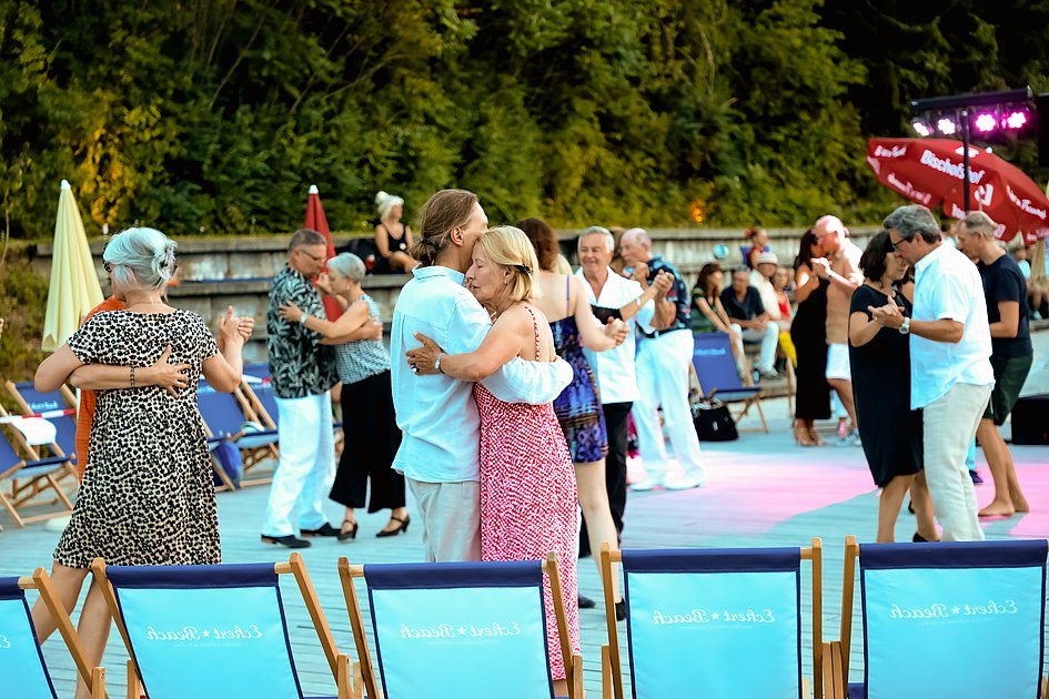 Die Bilder zeigen Impressionen der Tango Nacht am Eckert Beach mit Tanzpaaren, Schnupperkurs, Live-DJ, sommerlicher Atmosphäre und zahlreichen Gästen, die den Abschluss der Summer-Vibes-Reihe gemeinsam genießen.