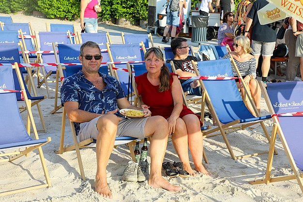 Die Bilder zeigen Eindrücke der Rock-Nacht am Eckert Beach. Zu sehen sind die Live-Auftritte der Bands Rusty Road Runners und ACBarbingCity´25, zahlreiche Besucherinnen und Besucher vor der Bühne sowie die sommerliche Atmosphäre am Strand. In beiden Bands stehen auch Dozenten der Eckert Schulen auf der Bühne. Die Aufnahmen zeigen Musiker, Publikum und die stimmungsvolle Beleuchtung während des Open-Air-Konzerts.