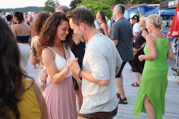 Die Diashow zeigt Eindrücke vom Salsa-Abend am Eckert Beach. Zu sehen sind tanzende Paare, Besucherinnen und Besucher im Publikum sowie die stimmungsvolle Atmosphäre der Veranstaltung am Abend.