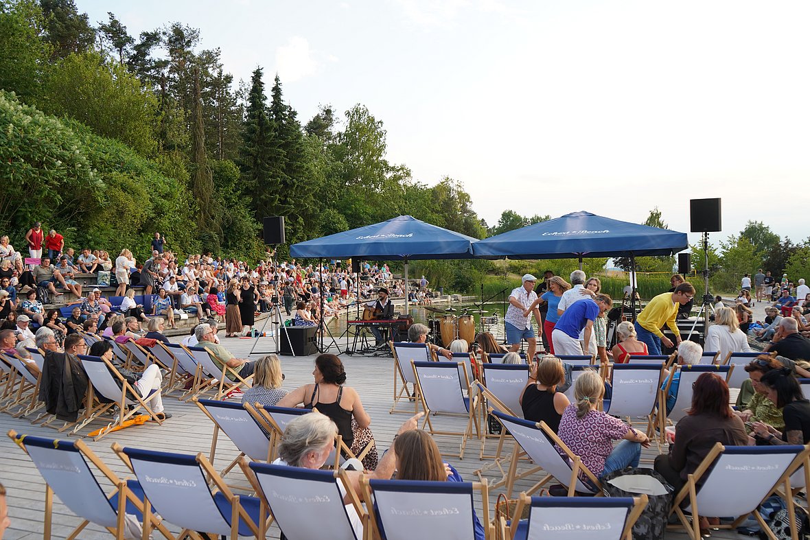 Zahlreiche Gäste genießen die entspannte Atmosphäre beim Open-Air-Konzert auf dem Eckert Beach – Musik, Tanz und Gemeinschaft unter freiem Himmel.