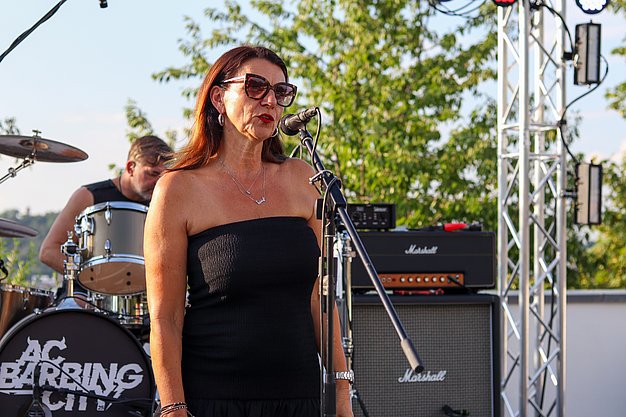 Die Bilder zeigen Eindrücke der Rock-Nacht am Eckert Beach. Zu sehen sind die Live-Auftritte der Bands Rusty Road Runners und ACBarbingCity´25, zahlreiche Besucherinnen und Besucher vor der Bühne sowie die sommerliche Atmosphäre am Strand. In beiden Bands stehen auch Dozenten der Eckert Schulen auf der Bühne. Die Aufnahmen zeigen Musiker, Publikum und die stimmungsvolle Beleuchtung während des Open-Air-Konzerts.